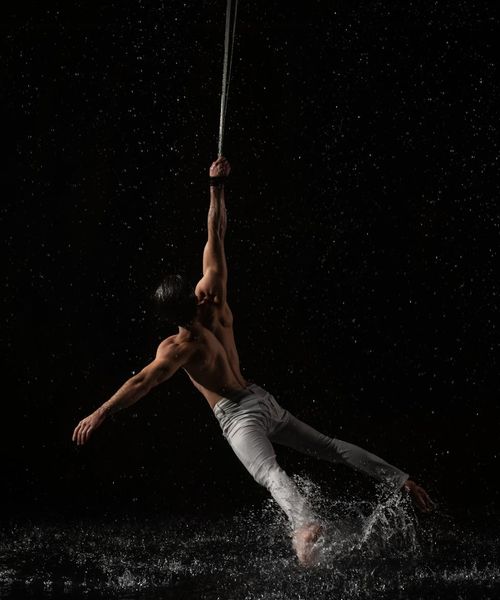 Man performing a controlled strength exercise in a minimalist dark environment.